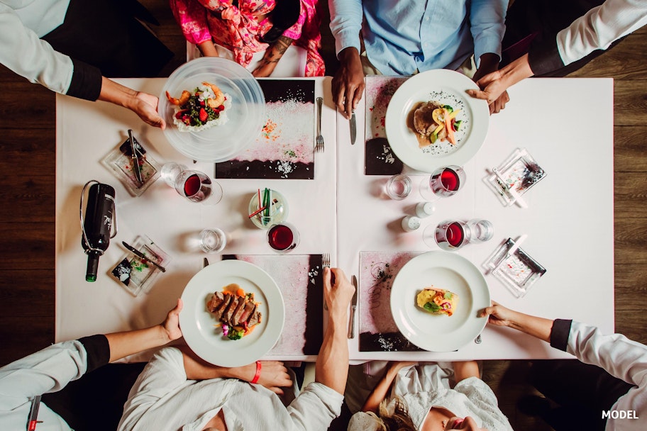 Mensen die gezellig aan het eten zijn in een restaurant - Tjingo.nl