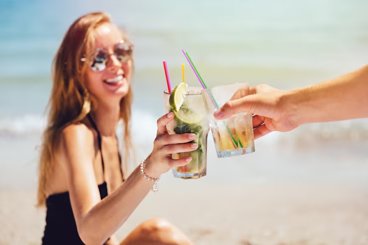 Vrouw proost met cocktail op het strand tijdens vakantie