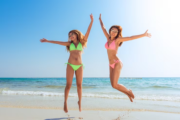 Twee vrouwen springen op het strand tijdens zonnige vakantie
