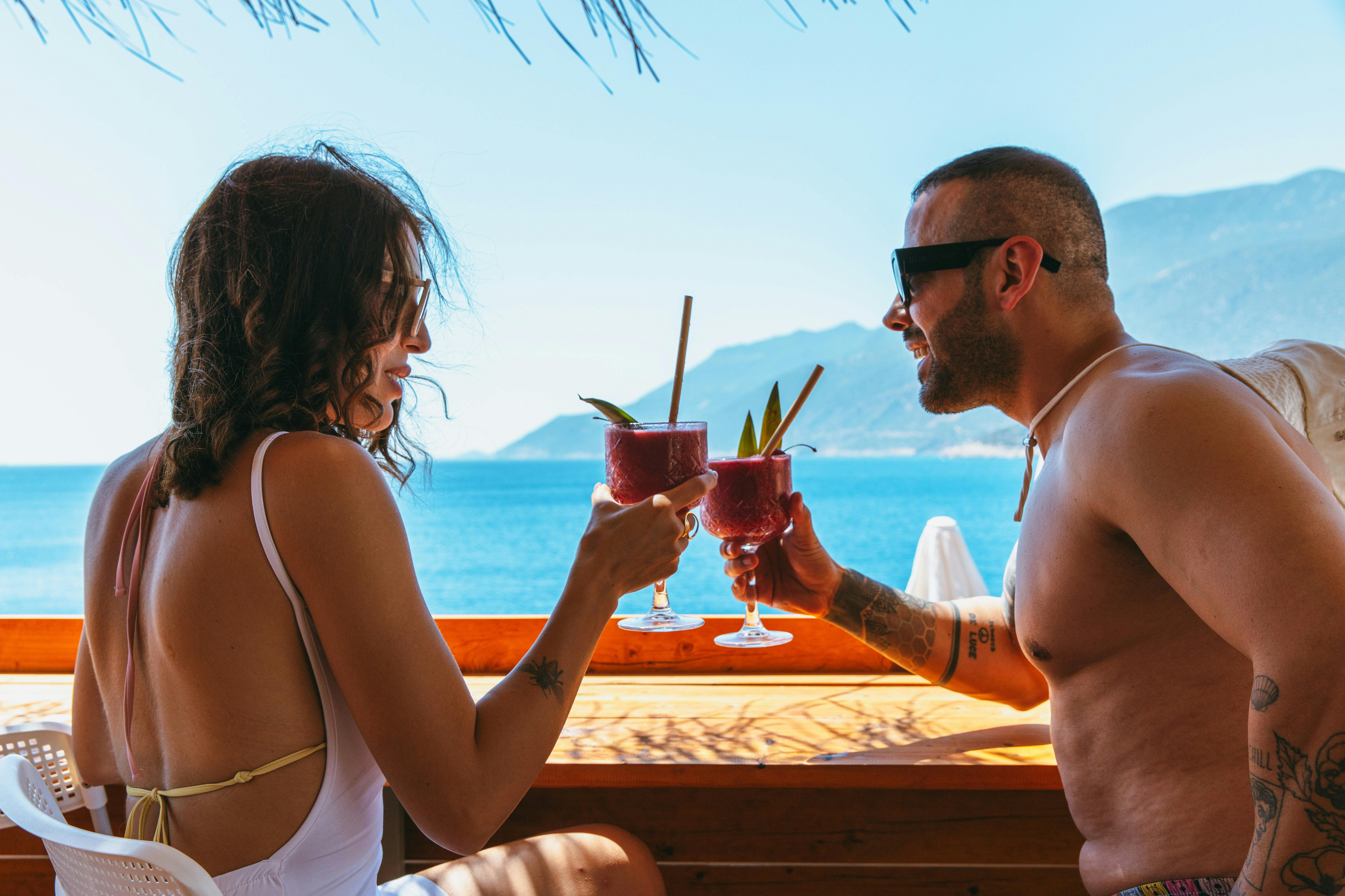 Koppel drinkt samen een cocktail met uitzicht op zee