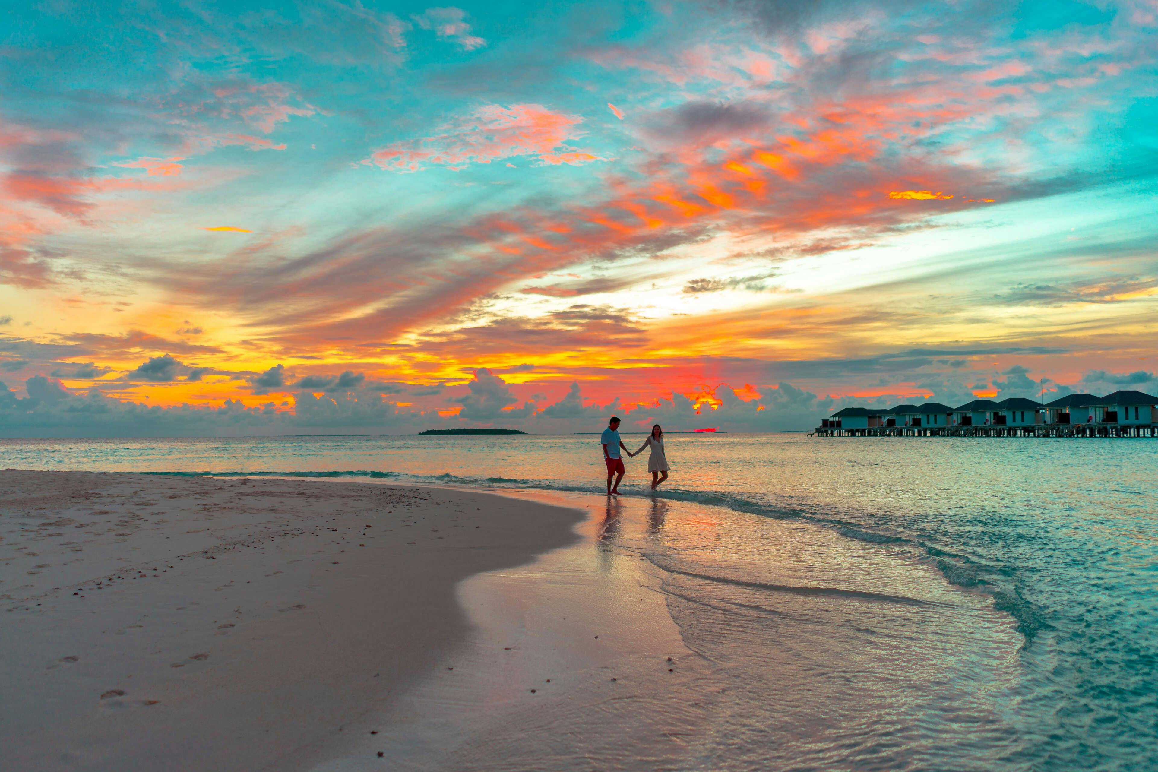 Koppel loopt over strand tijdens zonsondergang