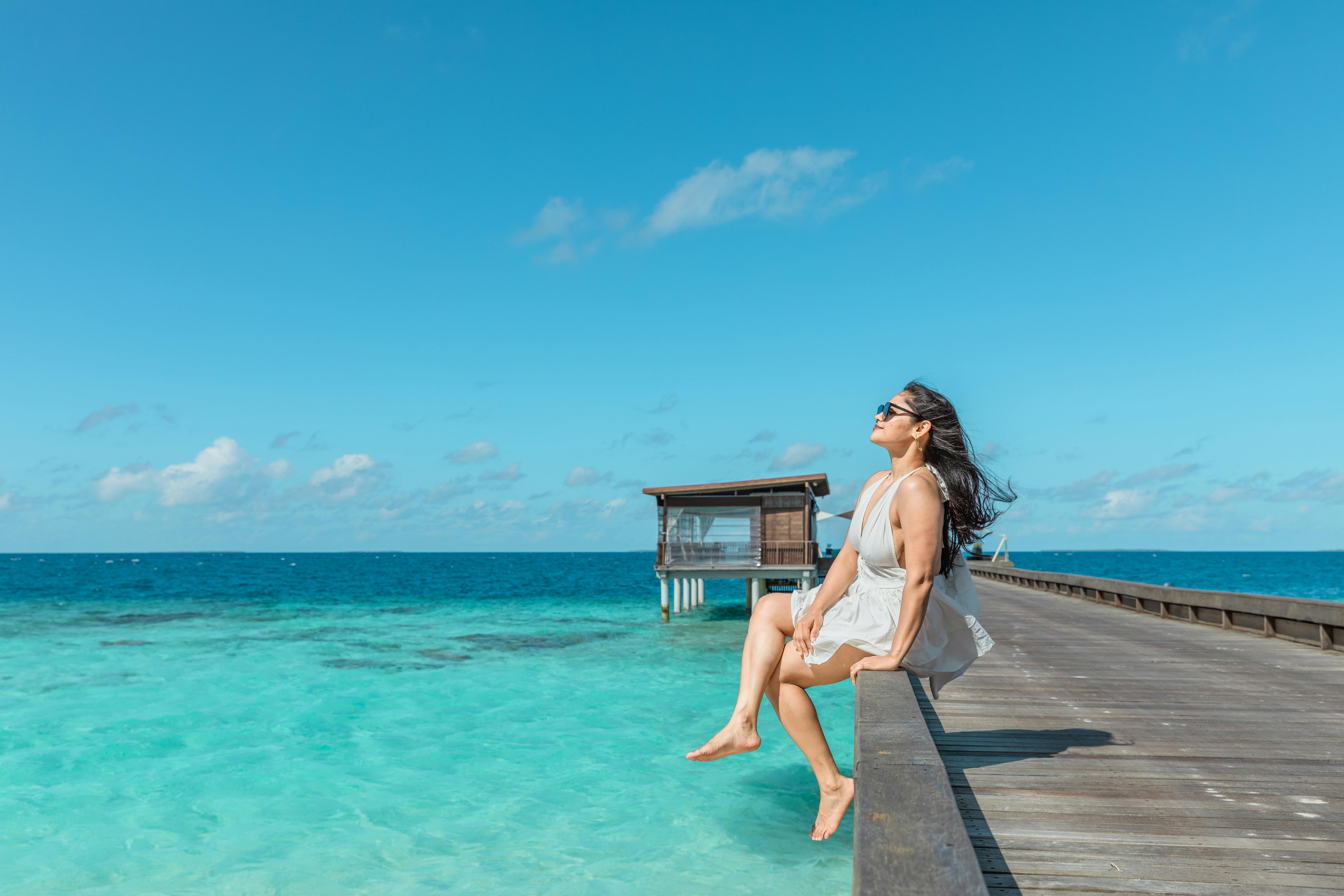 Vrouw zit op steiger bij helderblauw water